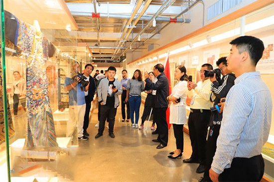 在愉悦家纺居家世博馆中,采访团正了解一件龙袍织品